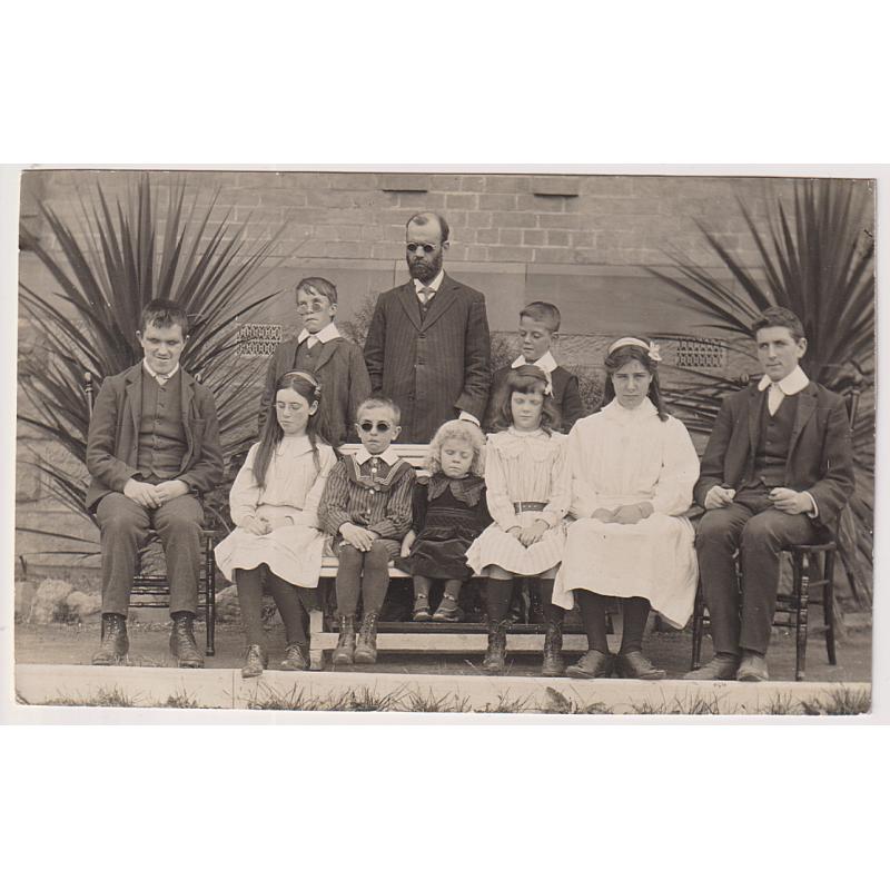 (BB1872) TASMANIA · c.1910: unused real photo card by J.W. Beattie featuring a portrait of blind students and their teacher, the photo taken outside the BLIND, DEAF & DUMB INSTITUTION at NORTH HOBART · fine condition