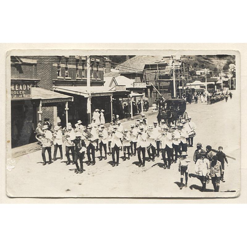 (VV10057) TASMANIA · WWI era real photo card by Rutter's Studio Burnie with a street view of a BRASS BAND (with scouts and nurses behind) marching past the town hall in Cattley Street · see description